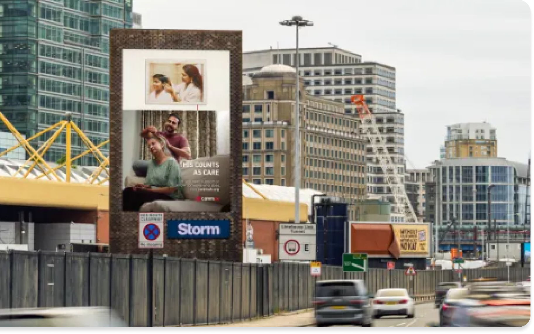 Painel publicitário em uma rua da cidade mostrando uma campanha com a frase 'Isso conta como cuidado' e imagens de pessoas.